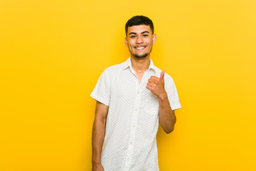 Young hispanic man smiling and raising thumb up