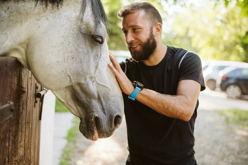 Summer day on the farm. Young man caress horse