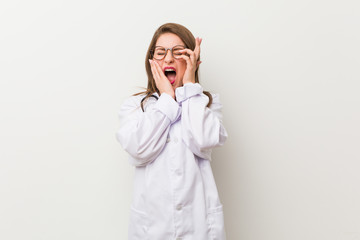 Young doctor woman against a white wall whining and crying disconsolately.