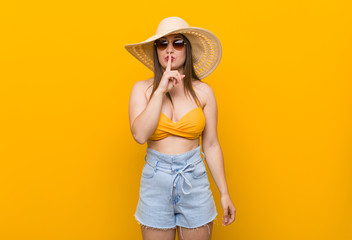 Young caucasian woman wearing a straw hat, summer look keeping a secret or asking for silence.