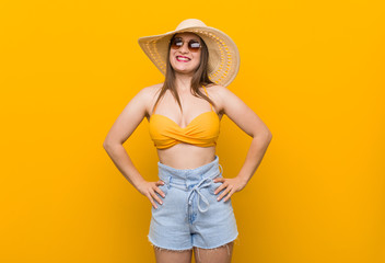 Young caucasian woman wearing a straw hat, summer look confident keeping hands on hips.