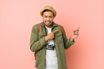 Young filipino traveler man shocked pointing with index fingers to a copy space.