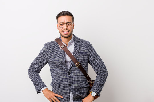 Young business filipino man against a white wall confident keeping hands on hips.