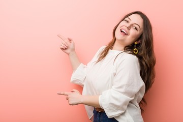 Young caucasian curvy woman standing against pink background