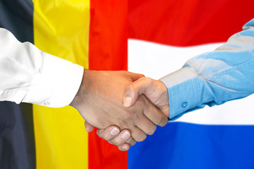 Business handshake on the background of two flags. Men handshake on the background of the Belgium and Dutch flag. Support concept