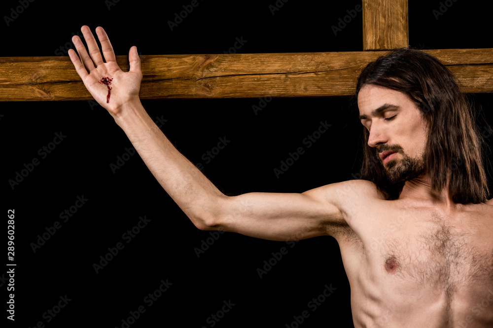 Wall mural jesus crucified on wooden cross isolated on black