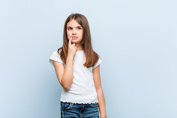 Cute girl looking sideways with doubtful and skeptical expression.