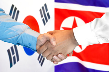 Fototapeta premium Business handshake on the background of two flags. Men handshake on the background of the South Korea and North Korea flag. Support concept