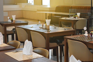 Modern interior of restaurant. Wooden furniture design and empty tables set ready for dinner.