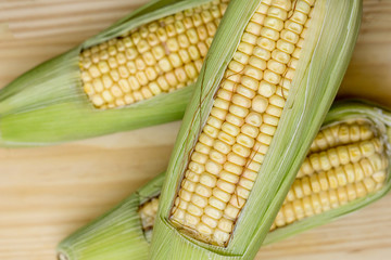 Closeup of raw corn cobs with straw over wood