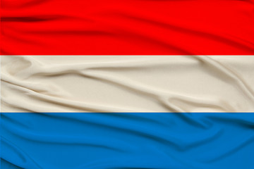 beautiful photo of the Luxembourg national flag on delicate shiny silk with soft draperies, the concept of state power, country life, horizontal, close-up, copy space