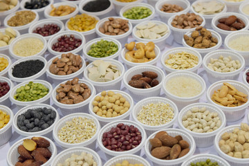 Cereal grains, seeds, beans on white plastic plate.