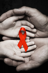 AID red ribbon in hand on a black wooden background.black and white.