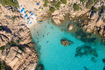 View from above, stunning aerial view of a small beach with beach umbrellas and people swimming in...