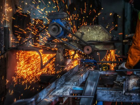 worker grinding cutting metal sheet with grinder machine overwrites the master of welding seams angle grinder and sparks. Electric grinder in the industrial 