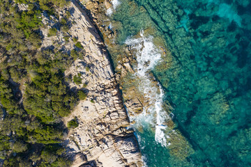 View from above, stunning aerial view of a green rocky coast bathed by a beautiful turquoise sea. (Emerald Coast) Sardinia, Italy.