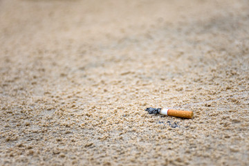 Cigarette stub throw on the sand by human in the beach it's cause of garbage in ocean and environmental pollution.