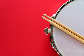 Drum and drum stick on red table background, top view, music concept