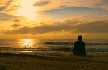  Indian woman meditating on morning sunrise beach