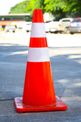 Orange and white traffic cone on concrete ground floor.