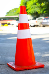 Orange and white traffic cone on concrete ground floor.