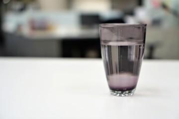 glass of water on white table with blurred background.