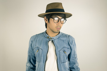 Young Asian Man in Jeans or Denim Jacket Wear Eyeglasses and Hat in Vintage Tone