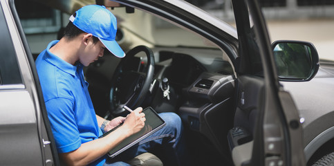 Young delivery man checking the products to customer with tablet while sitting on the car