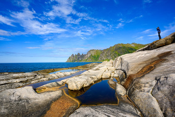 Photographer standing on the rocks to take a photo, Tungeneset Is a beautiful and popular viewpoint in the senja national park in northern Norway.