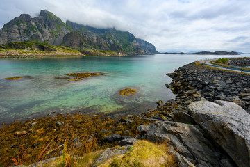 Viewpoint close to Henningsvaer, mountains, sea and rocks during the cloudy season in summer at the Lofoten Islands in Henningsvær, northern Norway