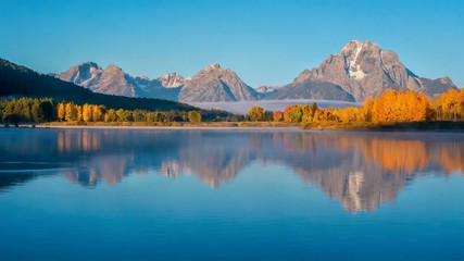 A beautiful early morning landscape at Oxbow Bend in the Snake River, with Mount Moran and autumn tree color reflected in the smooth water. Grand Teton National Park, Wyoming.