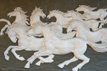 The wall is decorated with stone carvings in the shape of eight running horses.