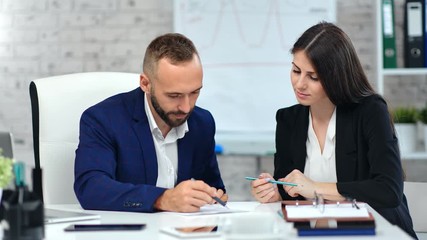 Male boss making signature on paper contract agreement using pen looking on data at workplace - Powered by Adobe