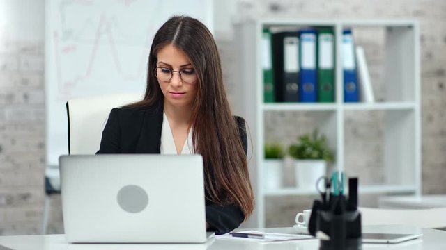Professional female marketologist in suit working using laptop pc at modern light office interior