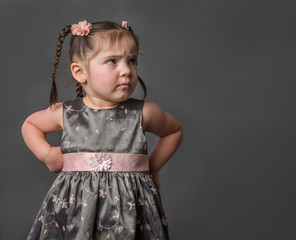 Adorable grumpy frustrated unhappy toddler girl with hands on hips