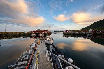 Fishing boat and red village Reflecting the water in the evening at Ballstad, Northern Norway, Rorbu is the traditional home of Norwegian fishermen.