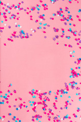 Festive party holiday colorful confetti on pink pastel background with copy space.