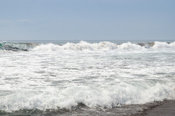 Waves breaking on black sand beach