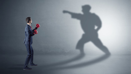 Fototapeta na wymiar Businessman fighting with his strong karate man shadow