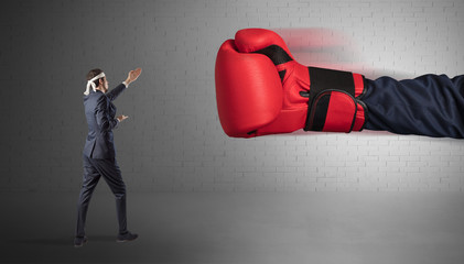 Tiny businessman fighting with boxing gloves