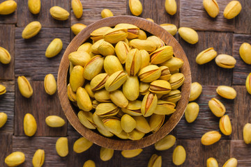 shelled pistachios, roasted nuts with saffron in wooden bowl, top view.