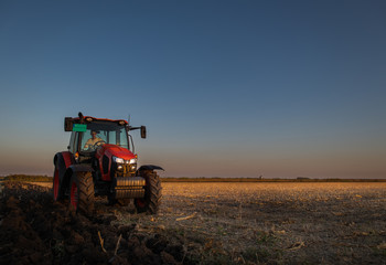 Tractor plowing fields in sunset