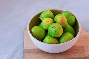 Bowl with figs on a wooden board, soft focus