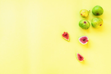Whole green figs and sliced on a yellow background, flat lay, copy space
