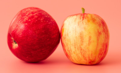 Two red apples on a pink background
