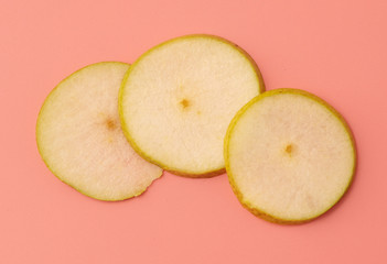 Three pieces of pear on a pink background