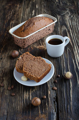 Fototapeta na wymiar Coffee cake with macadamia nuts and cup of coffee on dark wooden background