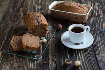 Coffee cake with macadamia nuts and cup of coffee on dark wooden background