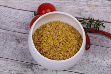 Raw bulgur in the bowl with tomatoes and garlic