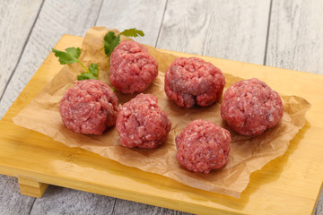 Raw meatball over wooden background